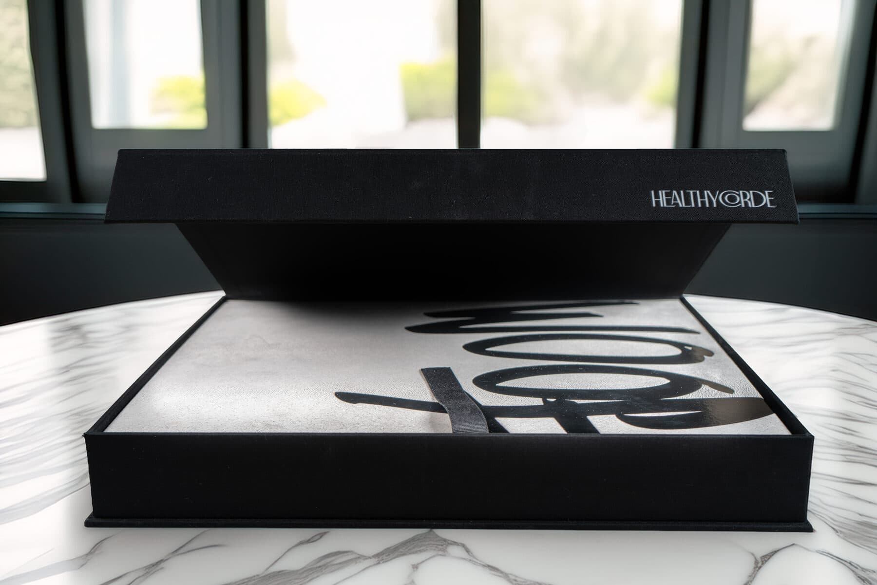 The WOOF clamshell wide open on a marble table by a window, daylight pouring in.