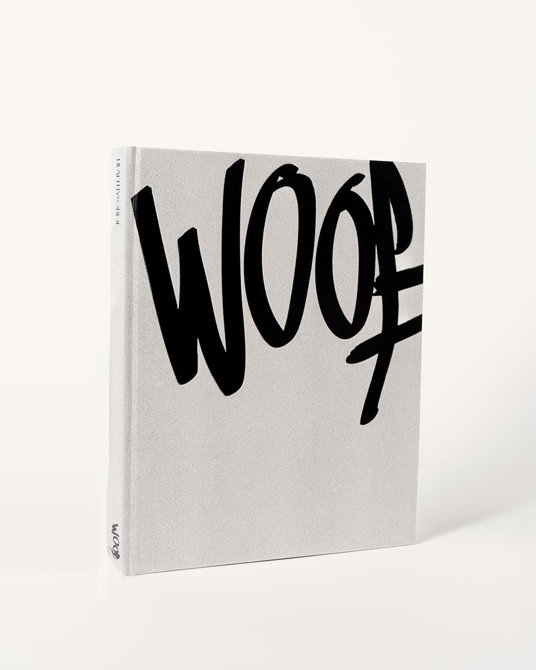 The bare cream WOOF cover standing upright, the brush mark in black, the EDITORIAL spine visible.